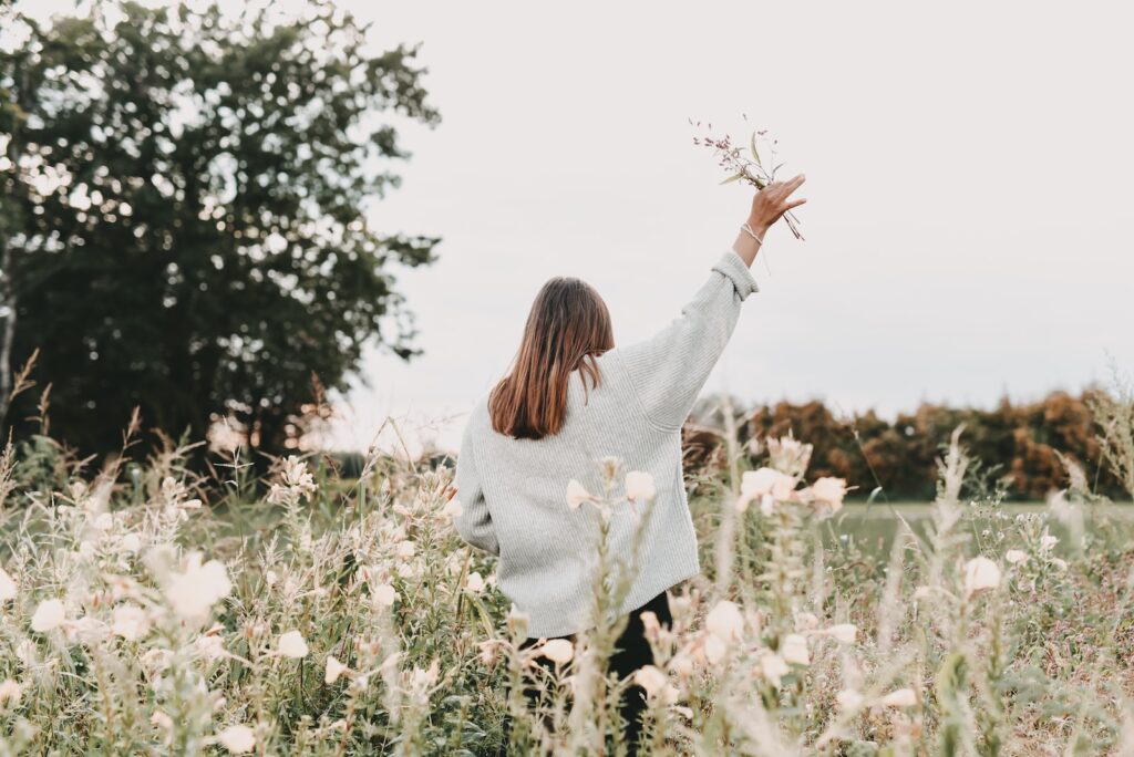 woman in white sweater standing on white flower field during daytime