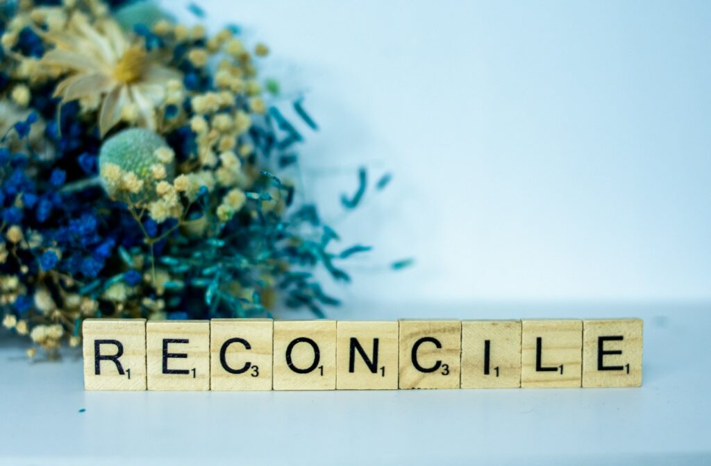 Photo of a scrabble block spelling the word reconcilie next to a bouquet for Called to reconcile... blog post