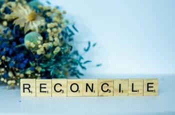 Photo of a scrabble block spelling the word reconcilie next to a bouquet for Called to reconcile... blog post